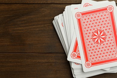 Photo of Deck of playing cards on wooden table, top view. Space for text