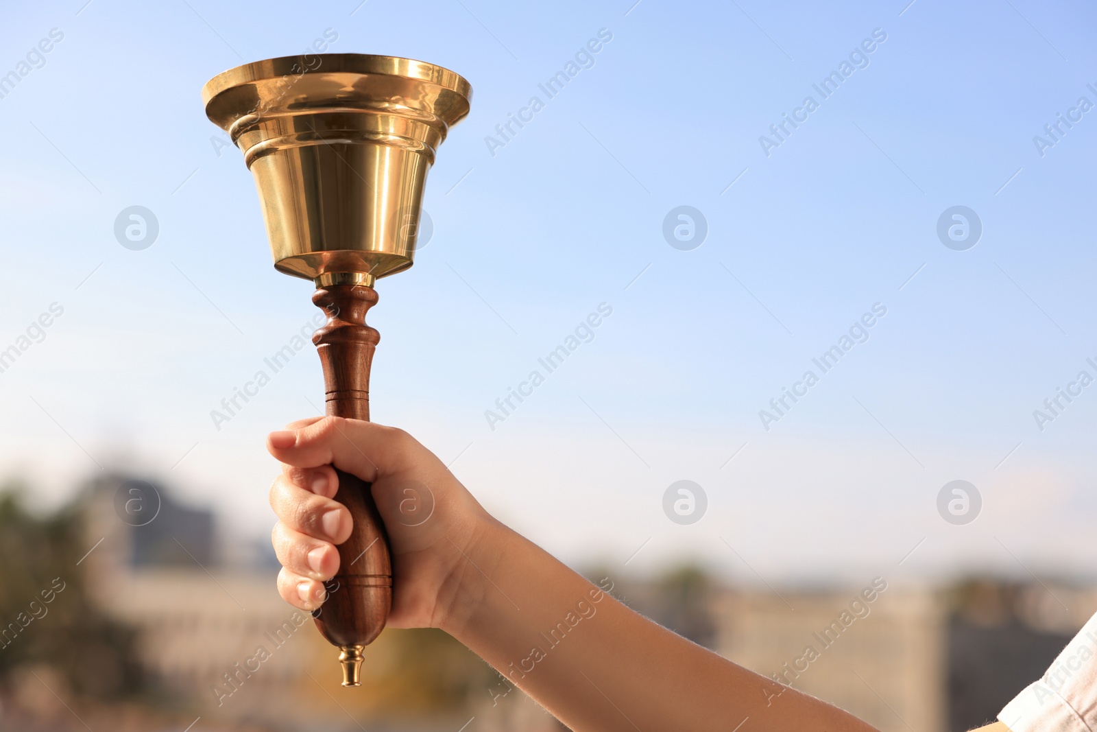 Photo of Pupil with school bell outdoors, closeup. Space for text