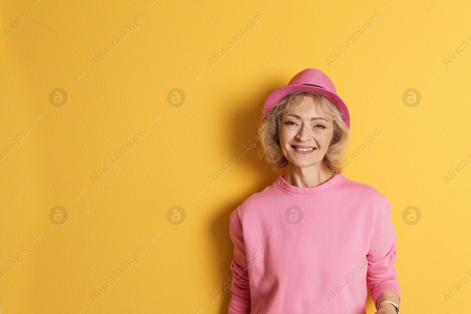 Photo of Portrait of mature woman in hipster outfit on color background. Space for text
