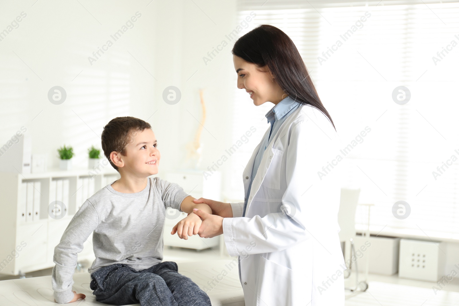 Photo of Professional orthopedist examining little patient's arm  in clinic