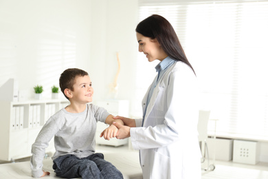 Professional orthopedist examining little patient's arm  in clinic