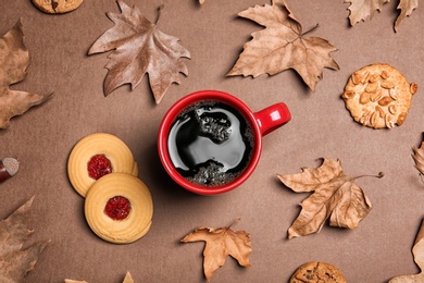 Flat lay composition with hot cozy drink and autumn leaves on color background