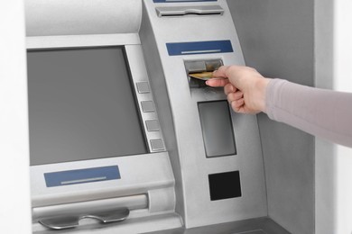 Woman inserting credit card into grey cash machine, closeup