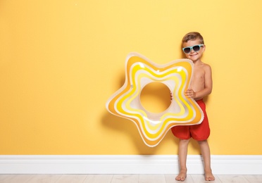 Photo of Cute little boy with bright star shaped inflatable ring near color wall