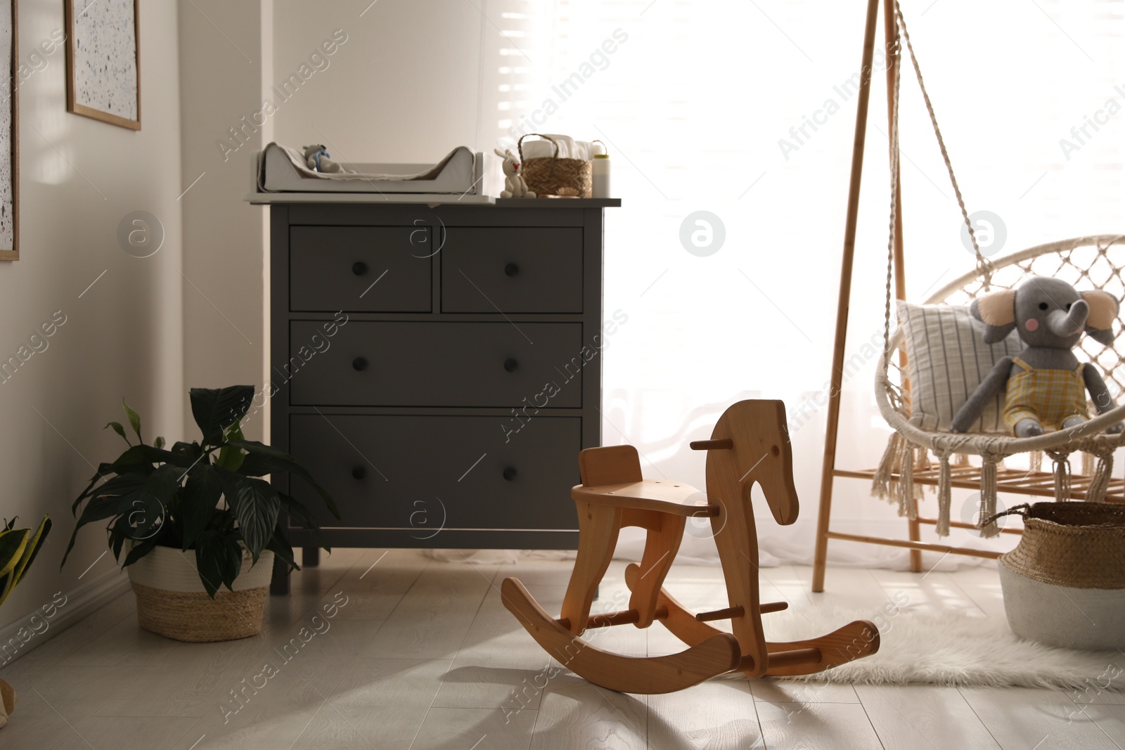 Photo of Baby room interior with modern changing table and wooden swing