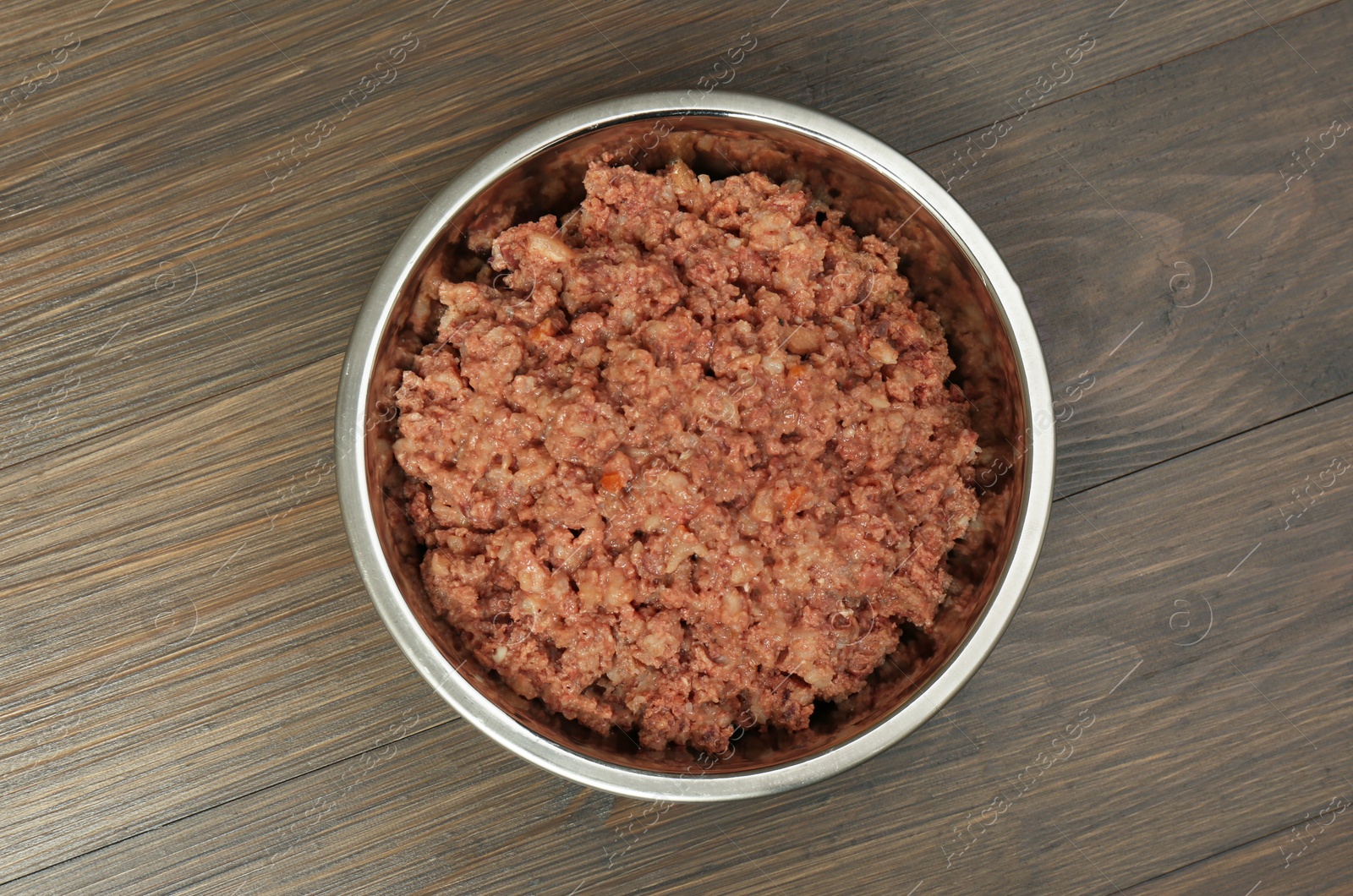 Photo of Wet pet food in feeding bowl on wooden background, top view