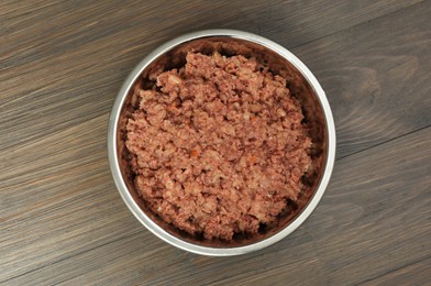 Photo of Wet pet food in feeding bowl on wooden background, top view