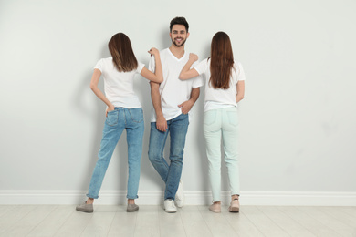 Photo of Group of young people in stylish jeans near light wall