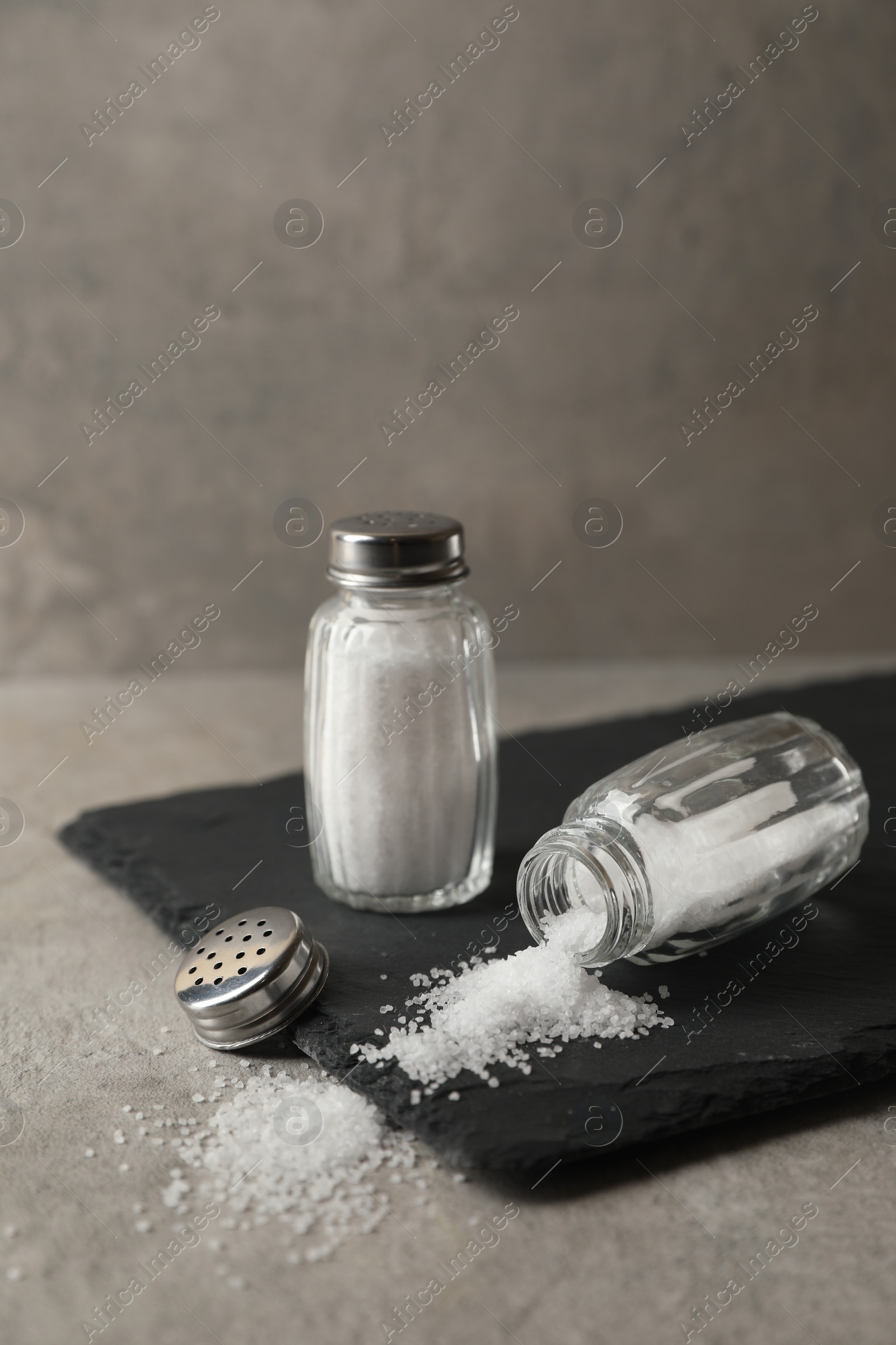 Photo of Natural salt in shakers on grey table