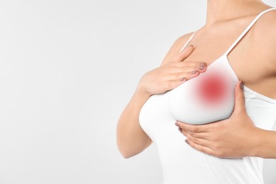 Woman checking her breast on white background, closeup