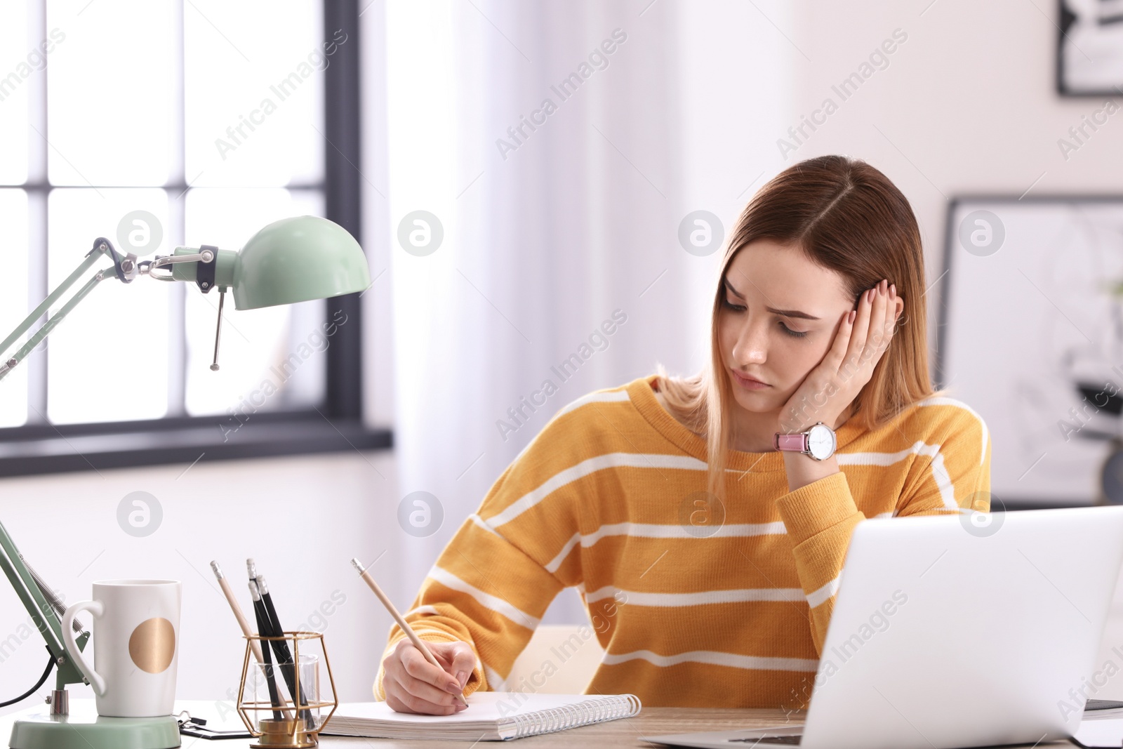 Photo of Emotional teenage girl doing homework in her room