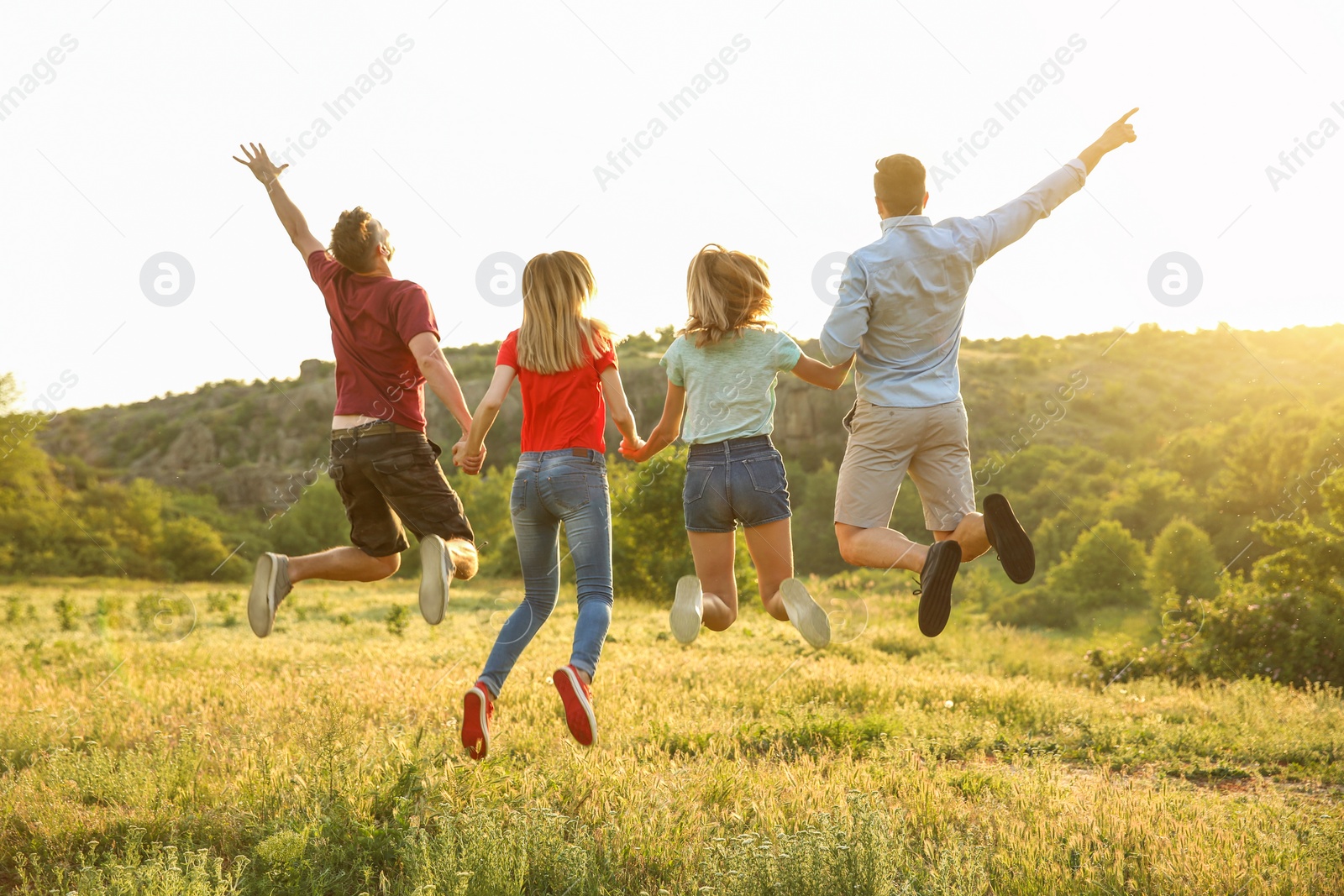 Photo of Happy young people jumping in wilderness. Camping season