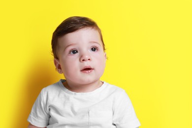 Photo of Cute little baby boy on yellow background, space for text