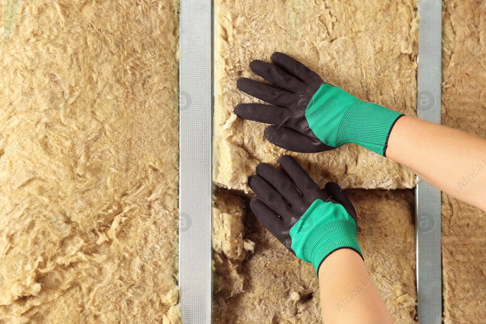 Photo of Worker installing thermal insulation material on wall, closeup