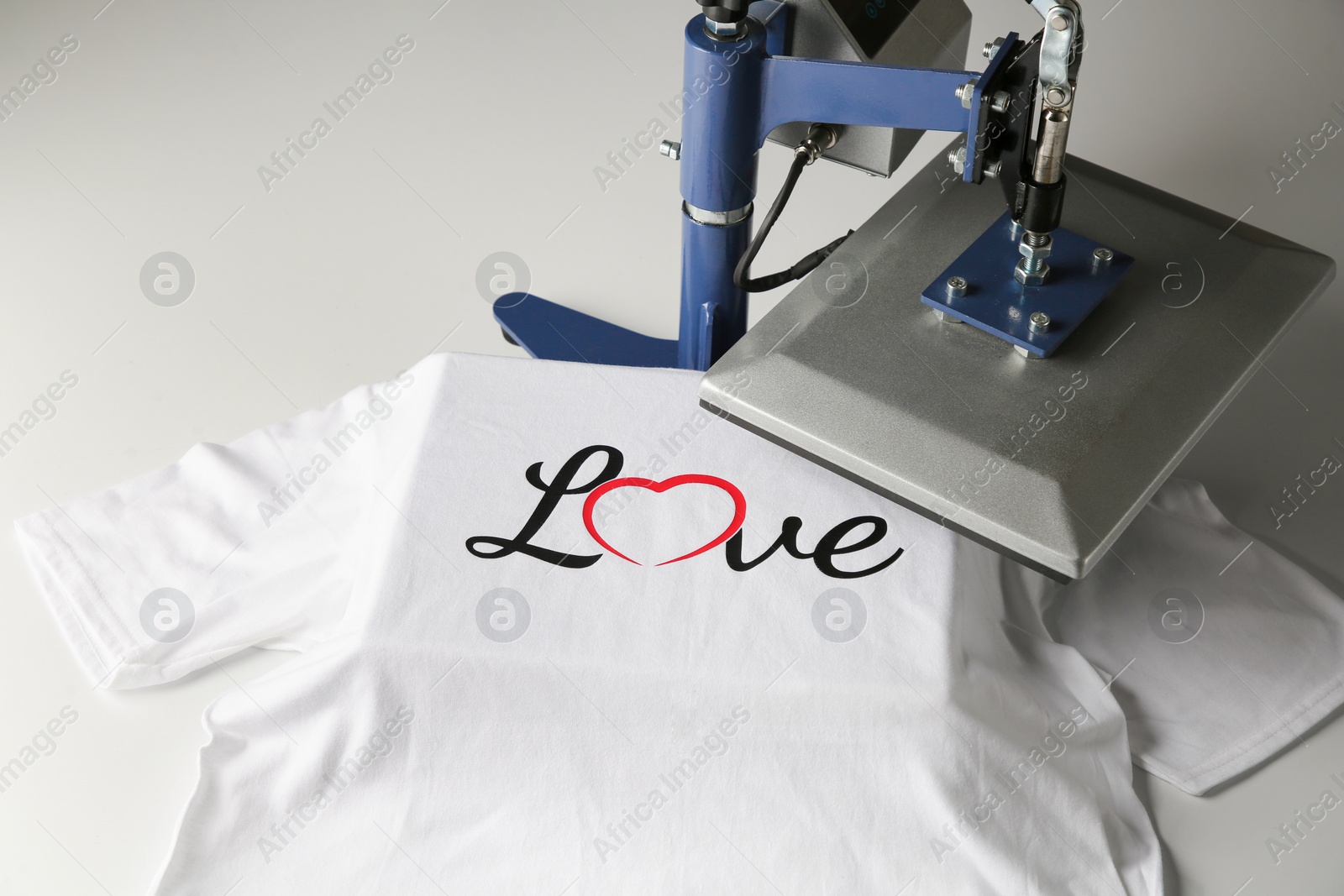 Photo of Printing logo. Heat press with t-shirt on white table