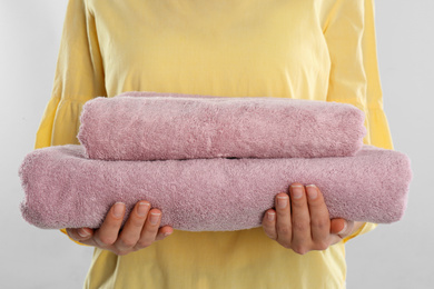 Woman holding fresh towels on light blue background, closeup