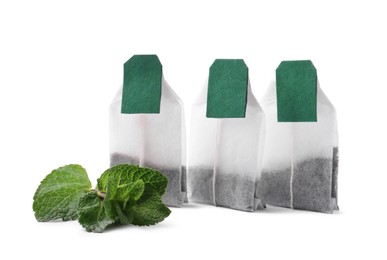 Photo of New tea bags with labels and mint on white background