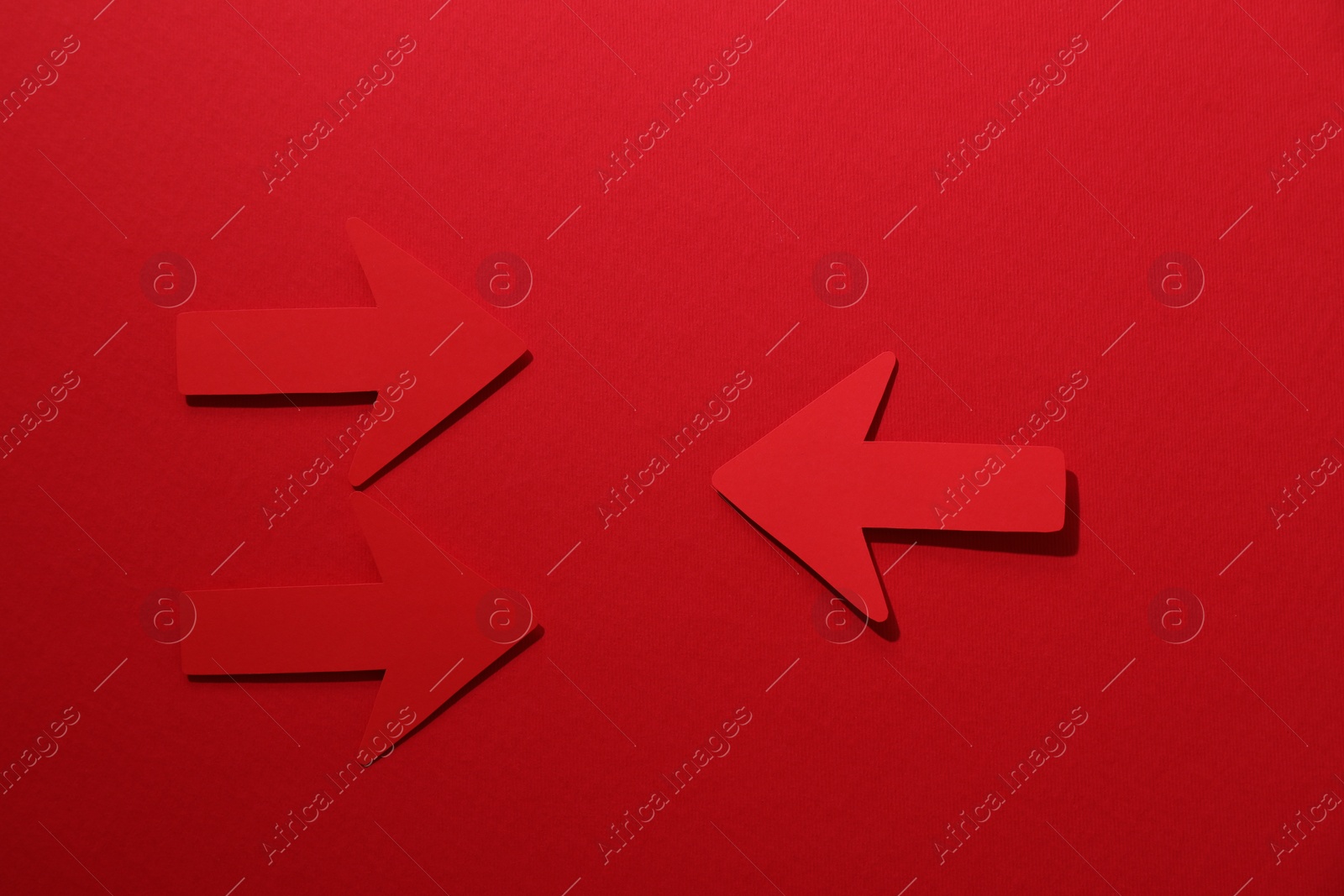 Photo of Paper arrows on red background, flat lay