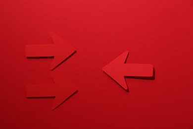 Paper arrows on red background, flat lay