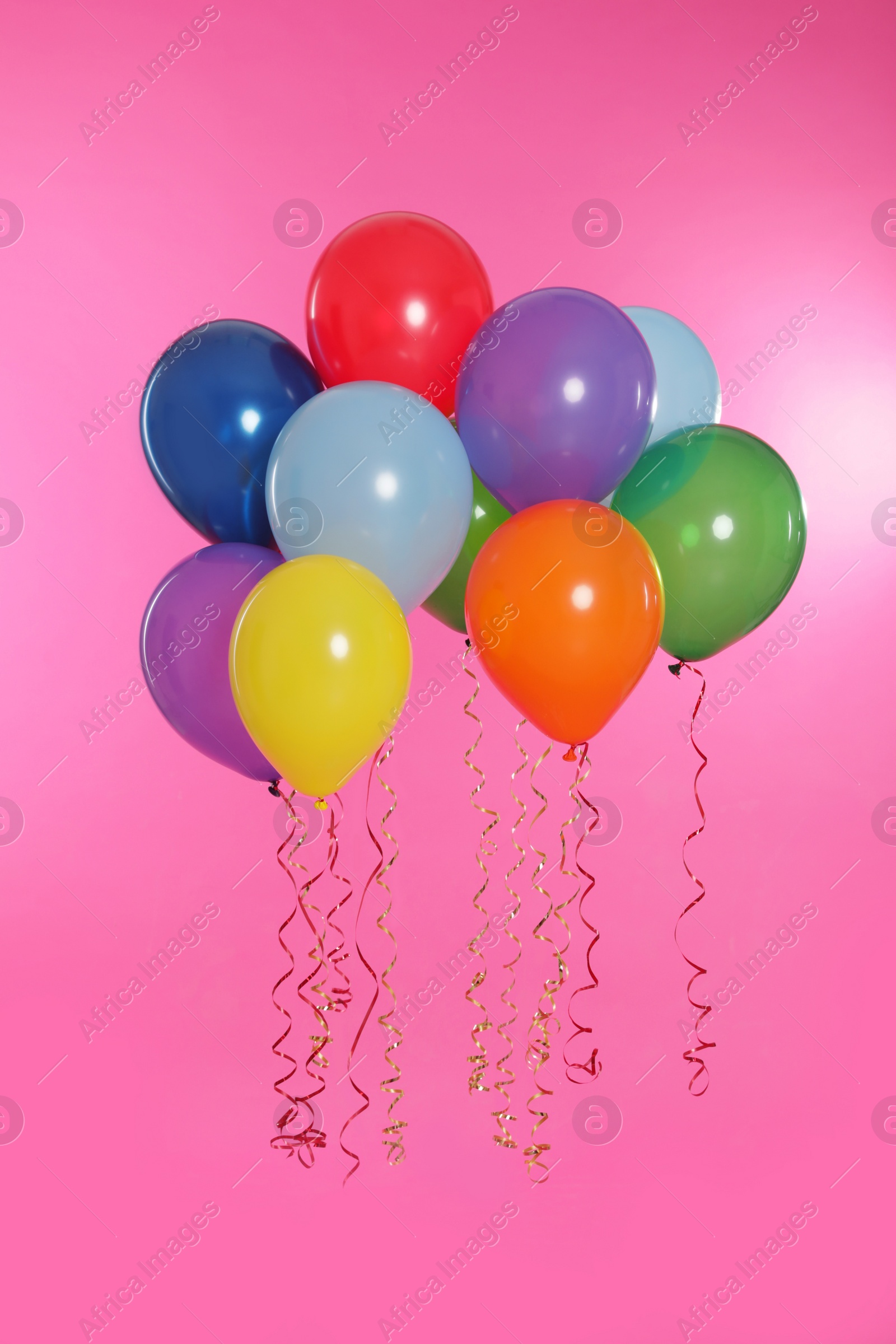 Photo of Many bright balloons floating on color background