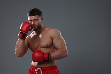 Photo of Man in boxing gloves on grey background. Space for text