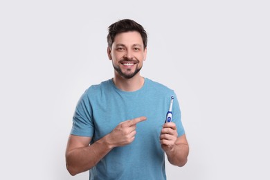 Photo of Happy man holding electric toothbrush on white background