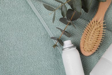 Dry shampoo sprays, hairbrush and eucalyptus branches on towel, flat lay. Space for text