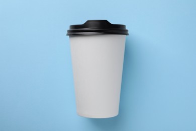 Photo of One paper cup on light blue background, top view. Coffee to go