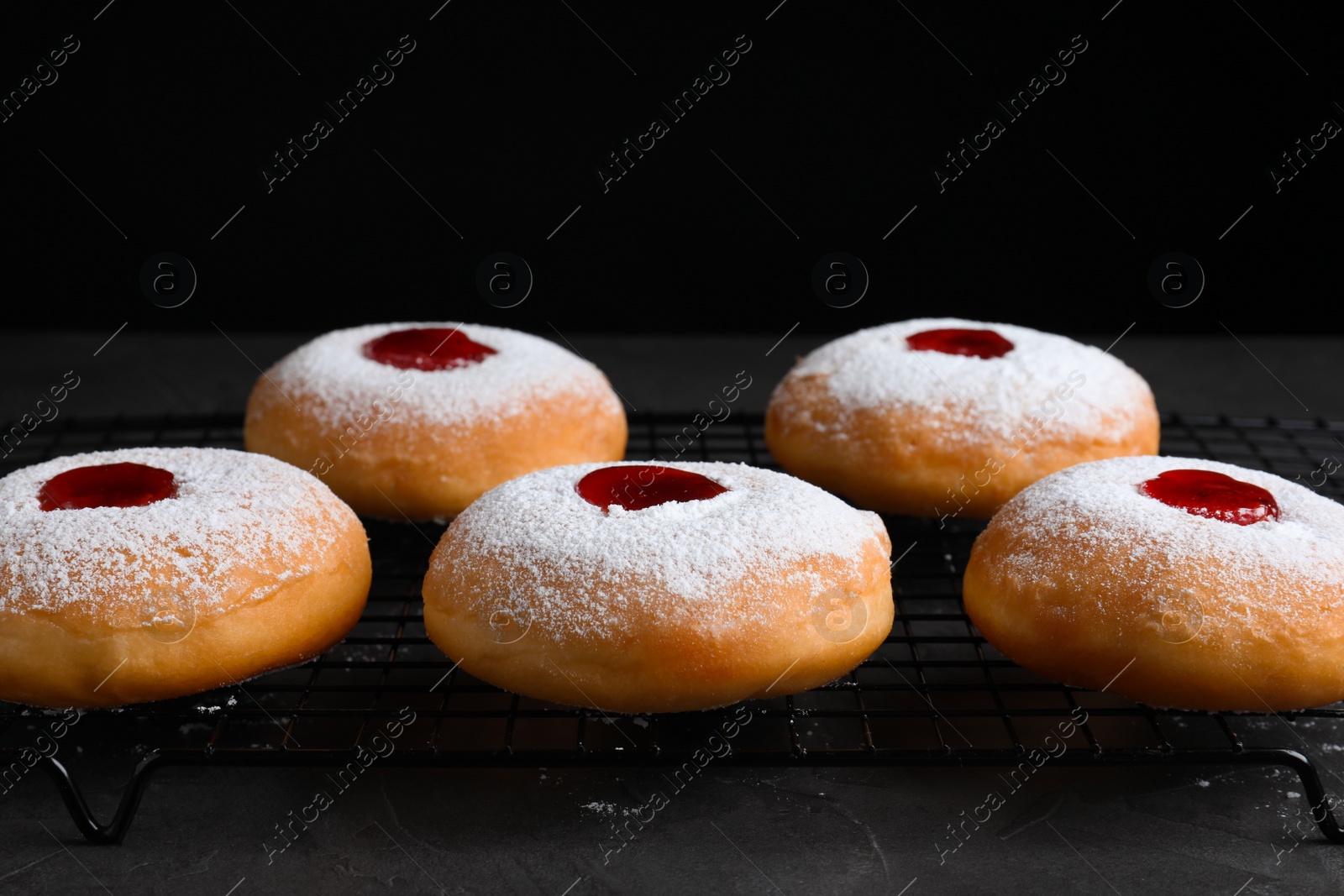 Photo of Hanukkah doughnuts with jelly and sugar powder on grey table