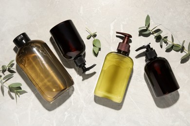 Photo of Shampoo bottles and leaves on white textured table, flat lay