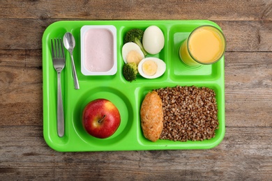 Serving tray with healthy food on wooden background, top view. School lunch