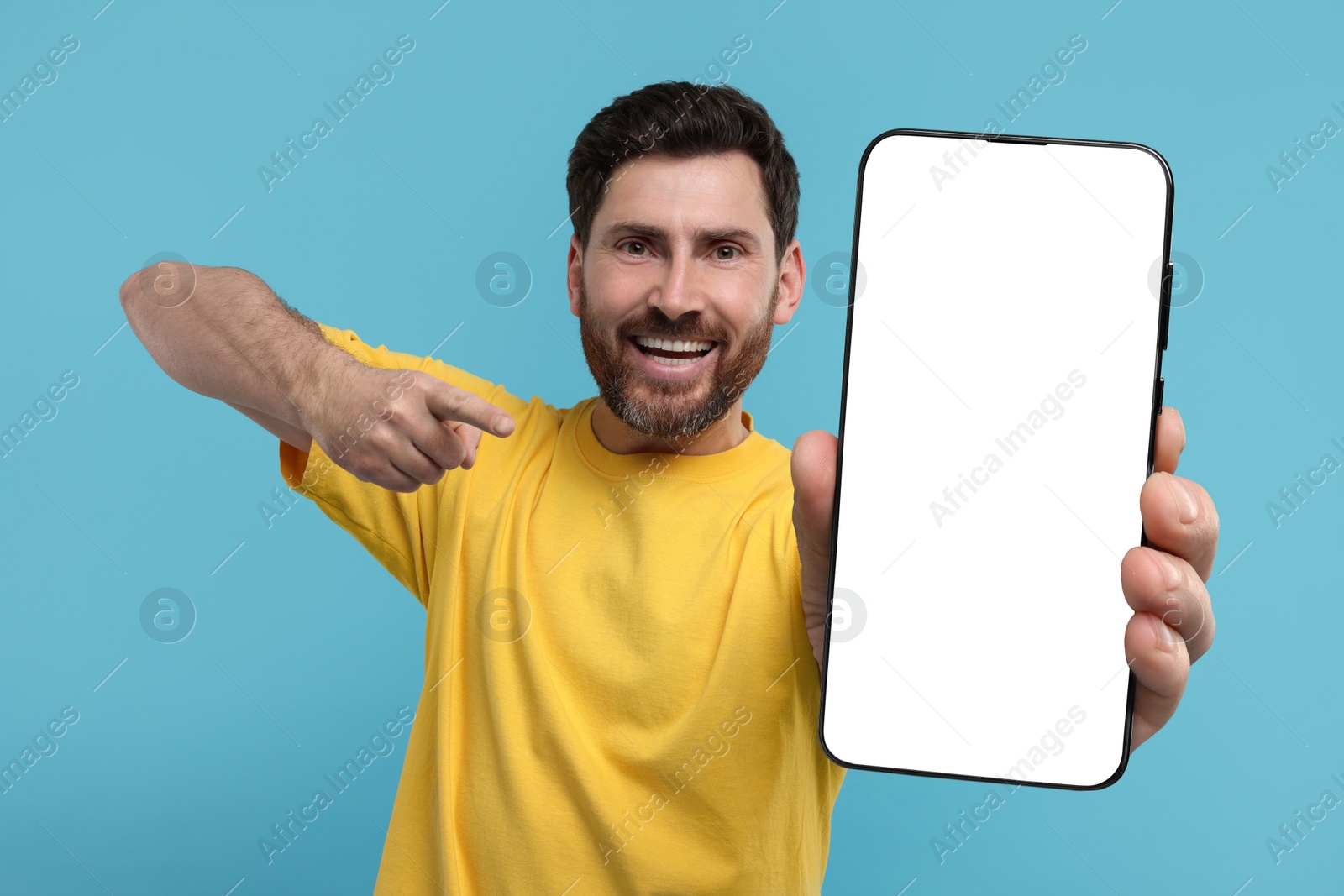 Image of Happy man holding smartphone with empty screen on light blue background