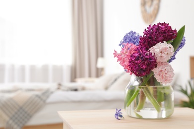 Photo of Beautiful hyacinths in glass vase on table indoors, space for text. Spring flowers