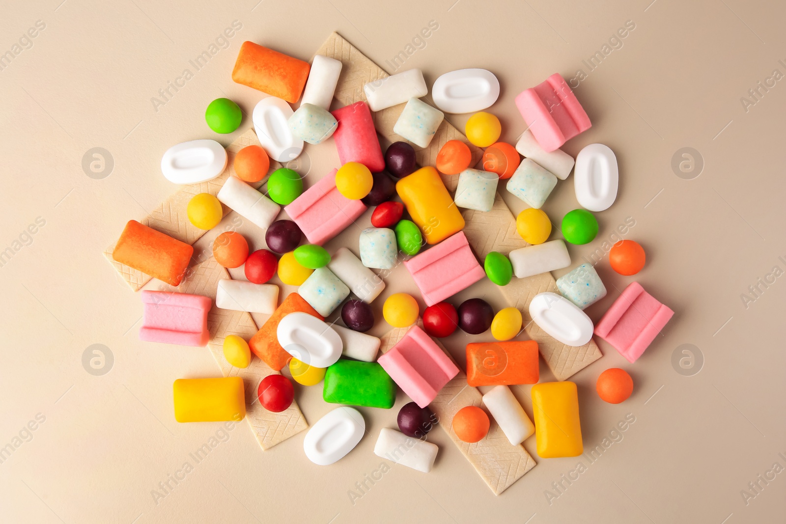 Photo of Many different chewing gums on beige background, flat lay