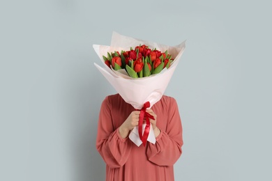 Woman with red tulip bouquet on light grey background. 8th of March celebration