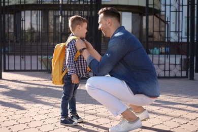 Young man saying goodbye to his little child near school