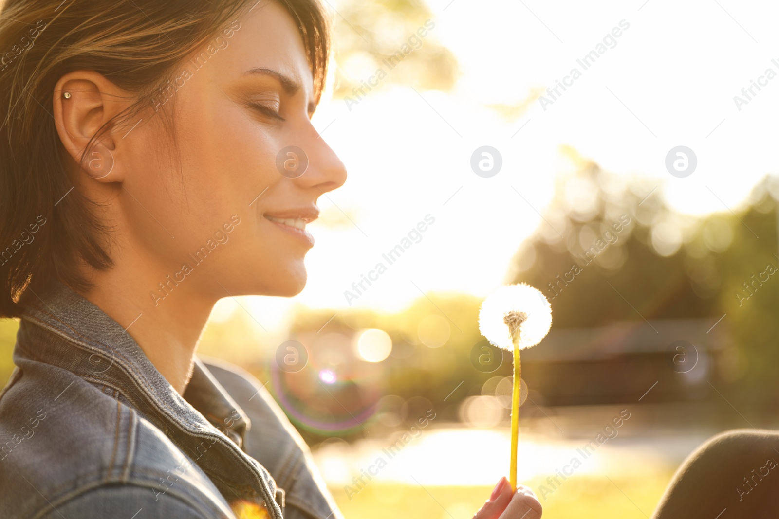 Photo of Young woman with dandelion in park on sunny day. Allergy free concept