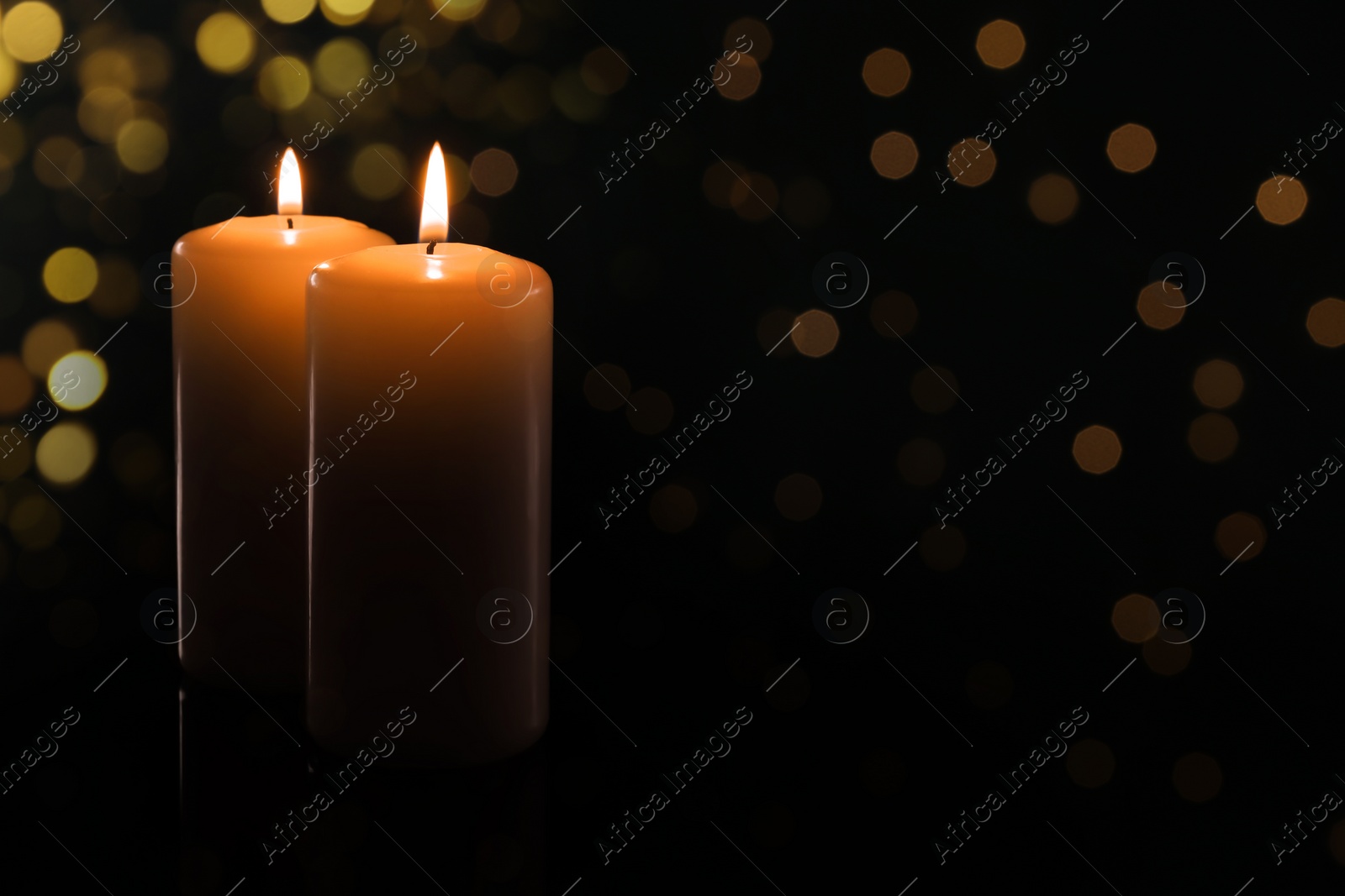 Image of Wax candles burning on black background with blurred lights. Bokeh effect