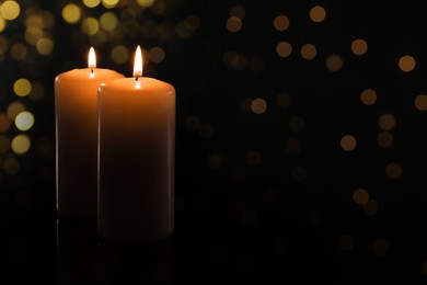 Image of Wax candles burning on black background with blurred lights. Bokeh effect