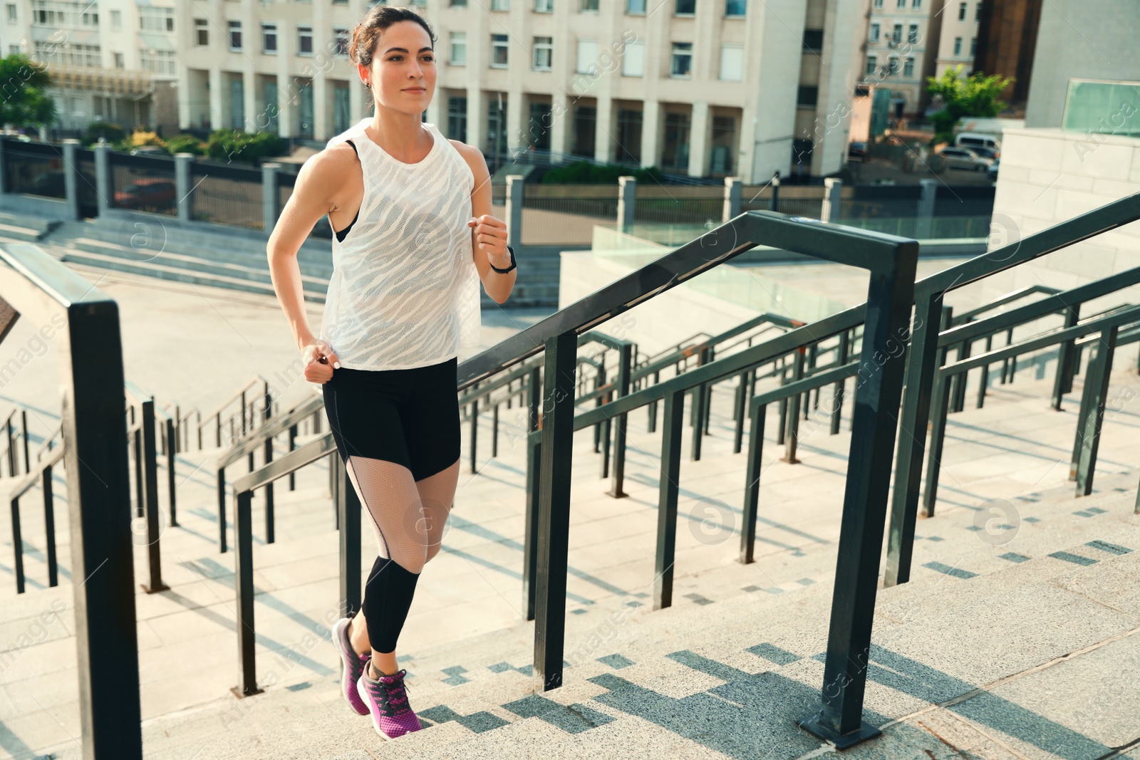 Photo of Sporty young woman running upstairs on sunny day