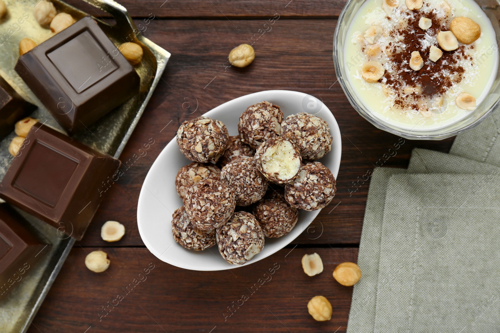 Photo of Delicious sweet chocolate candies and ingredients on wooden table, flat lay