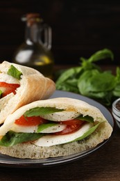Photo of Delicious pita sandwiches with mozzarella, tomatoes and basil on wooden table