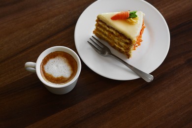 Photo of Delicious cake and cup of hot coffee on wooden table, above view