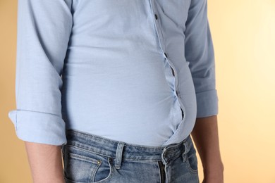 Photo of Overweight man in tight shirt on yellow background, closeup