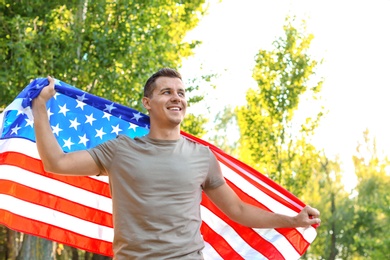 Man with American flag in park on sunny day