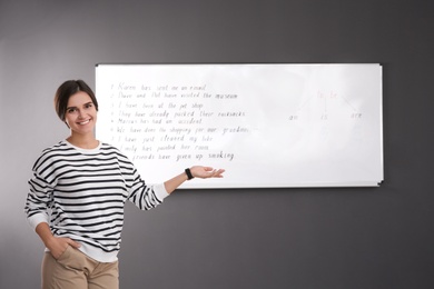 Happy English teacher near whiteboard at lesson
