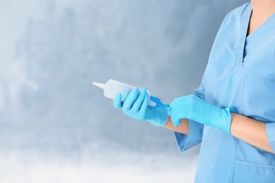 Photo of Doctor in medical gloves with large syringe on color background. Space for text