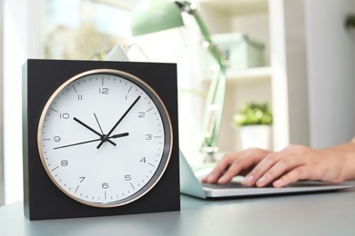 Photo of Stylish analog clock on table in office. Time to work