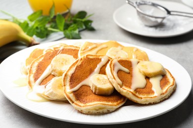 Tasty pancakes with sliced banana served on grey table, closeup