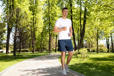 Photo of Young man on morning run in park, space for text. Fitness lifestyle